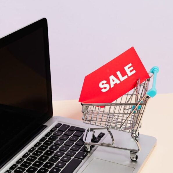 a red sale tag on a miniature shopping cart placed on a macbook laptop